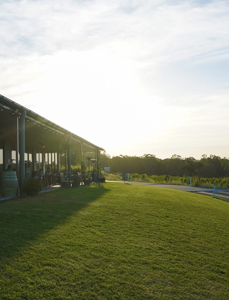 A modern building with an outdoor patio next to a grassy lawn at sunset.